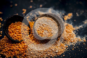 Close up of raw pink lentils in a clay bowl on wooden surface with its powder.