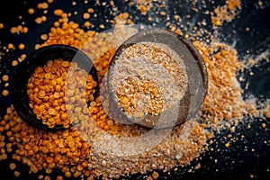 Close up of raw pink lentils in a clay bowl on wooden surface with its powder.