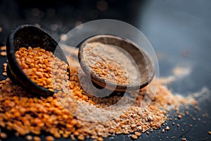 Close up of raw pink lentils in a clay bowl on wooden surface with its powder