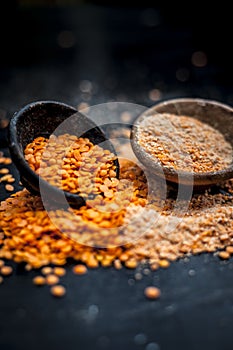 Close up of raw pink lentils in a clay bowl on wooden surface with its powder.