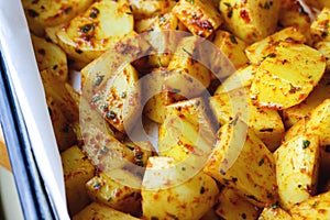 Close-up of raw potato slices in spices ready to be baked or roasted. Fresh potato wedges mixed with herbs and spices in a rustic