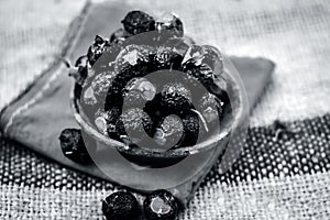 Close up of raw soap nuts in a clay bowl on brown colored surface.