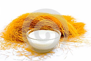 Close up of Raw vermicelli or sevee or seviyan or seviyaan isolated on white with a bowl of milk used to make kheer.