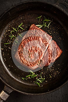 Close up raw wagyu beef striploin steak with pepper on dark pan. Restaurant