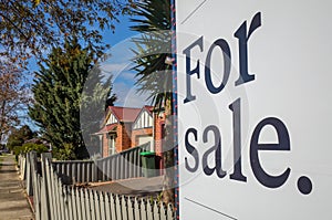 Close up of a real estate sign board with text  `for sale` , some suburban houses/Australian homes and pedestrian walkway as photo