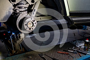 A close-up on the rear brake system of a car with hub and instruments on a lift in a vehicle repair workshop. Auto service