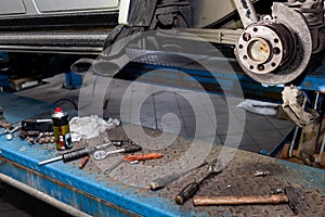 A close-up on the rear brake system of a car with hub and instruments on a lift in a vehicle repair workshop. Auto service