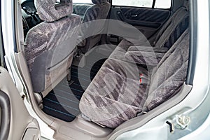 Close-up on rear seats with striped fabric upholstery in the interior of an old Japanese car in gray after cleaning
