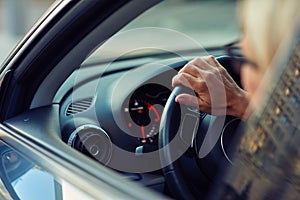 Close up rear view of a woman driving car through the city