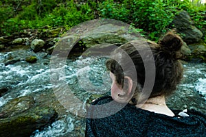 Close up Rear view of woman sitting by rushing water