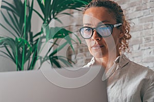 Close up rear view young woman using laptop and calculator, working on project, checking financial documents, sitting at table at