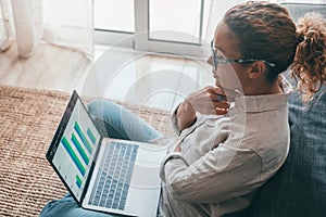 Close up rear view young woman using laptop and calculator, working on project, checking financial documents, sitting at table at