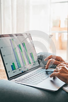 Close up rear view young woman using laptop and calculator, working on project, checking financial documents, sitting at table at