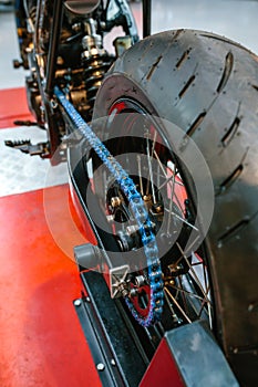 Close up of rear wheel and decorative blue chain on custom motorbike on factory