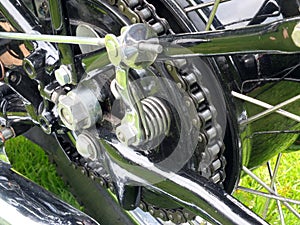 Close up of the rear wheel and drive chain of a black vintage motorcycle