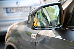 Close up of rearview mirror of a car parked near curb on the side of the street on a parking lot