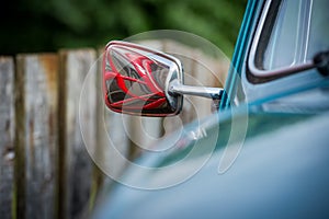 Close up of a rearview mirror reflecting a british phone booth