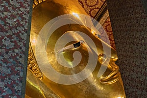 A close up of Reclining Buddha gold statue face. Wat Pho