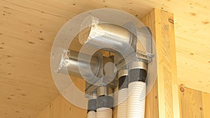 CLOSE UP: Recuperation system exchanger and two tubes run down a hardwood wall. photo