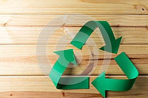 Close up of recycling symbol of paper green arrows on wooden background with copy space