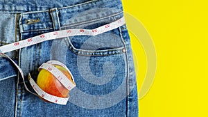 Close up of the red apple on blue jeans Wrapped around a tape measure