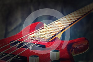 Close-up red bass guitar on dark background. Vintage toning with vignette