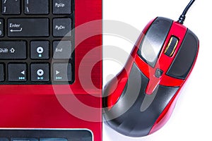 Close up of red and black computer mouse and laptop isolated on white background