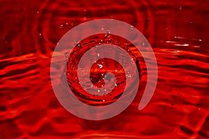 Close up of red BLOOD drop splash in Blood with orange background. Shiny rippled Surface texture and design.