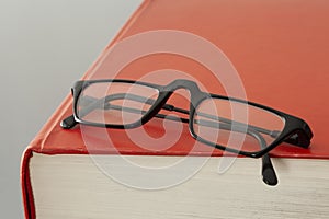 Close up on a red book cover and eye glasses with copy space for your text
