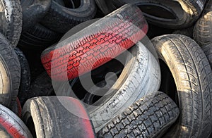 Close up of red car tires with tread in a pile of used tires