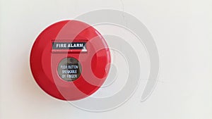 Close-up of red circular fire alarm with manual switch button to warn in case of fire emergency