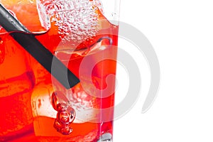 Close-up of red cocktail with ice cubes and straw on white background