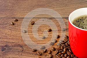 Close-up of Red Coffee Mug with Coffee and Coffee Beans on Wood
