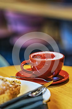 Close-up of red cup with tasty coffee cappuccino and soft foam