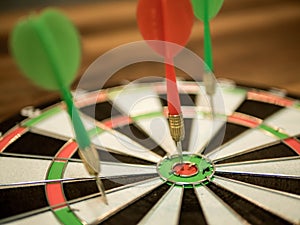 Close up red dart arrow hitting in the target center of dartboard, metaphor to target success, winner concept