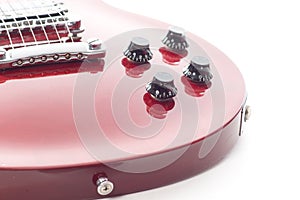 Close up of a red electric guitar with buttons and strings on a white background