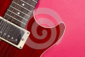 Close-up of red electric guitar on pink background. Musical concept of guitar music.