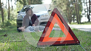 Close-up red emergency road sign with blurred anxious man crying and dead woman lying at background. Knocked down