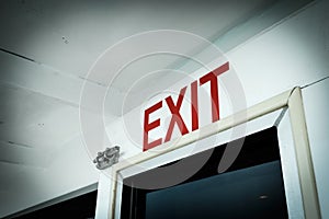 A close-up red exit directional sign with white background
