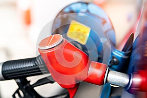 Close-up red fuel nozzle. Gasoline pump nozzle. Car fueling at gas station. Refuel fill up with petrol gasoline. Petrol pump