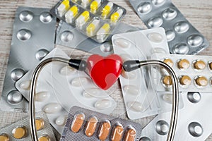 Close-up of a red heart made of stone, vitamins,pills, stethoscope