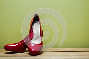 Close up of red high heels on green background.