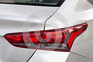 Close-up of a red LED rear brake light replaced after an accident on a white car in the back of a sedan after washing and cleaning