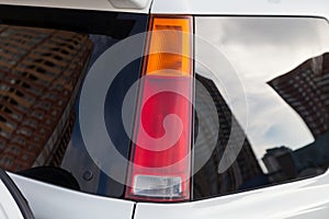 Close-up of a red LED rear brake light replaced after an accident on a white car in the back of an SUV after washing and cleaning