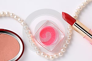 Close up on red lipstick, face powder, lipgloss and  pearl necklace isolated on white background with copy space for your text