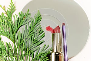 close up red lipstick and make up brush on the mirror on the beige background