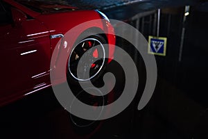 Close-up of red modern sport car, after rain in night city.