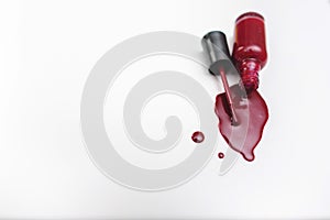 Close up of a red nail polish bottle and drop on white background