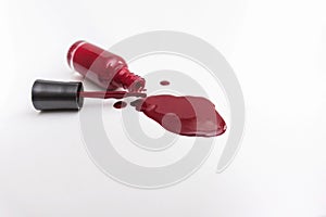 Close up of a red nail polish bottle and drop on white background