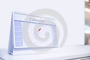 Close-up red pin on blank desk calendar and office equipment concept of event planner or personal organization for